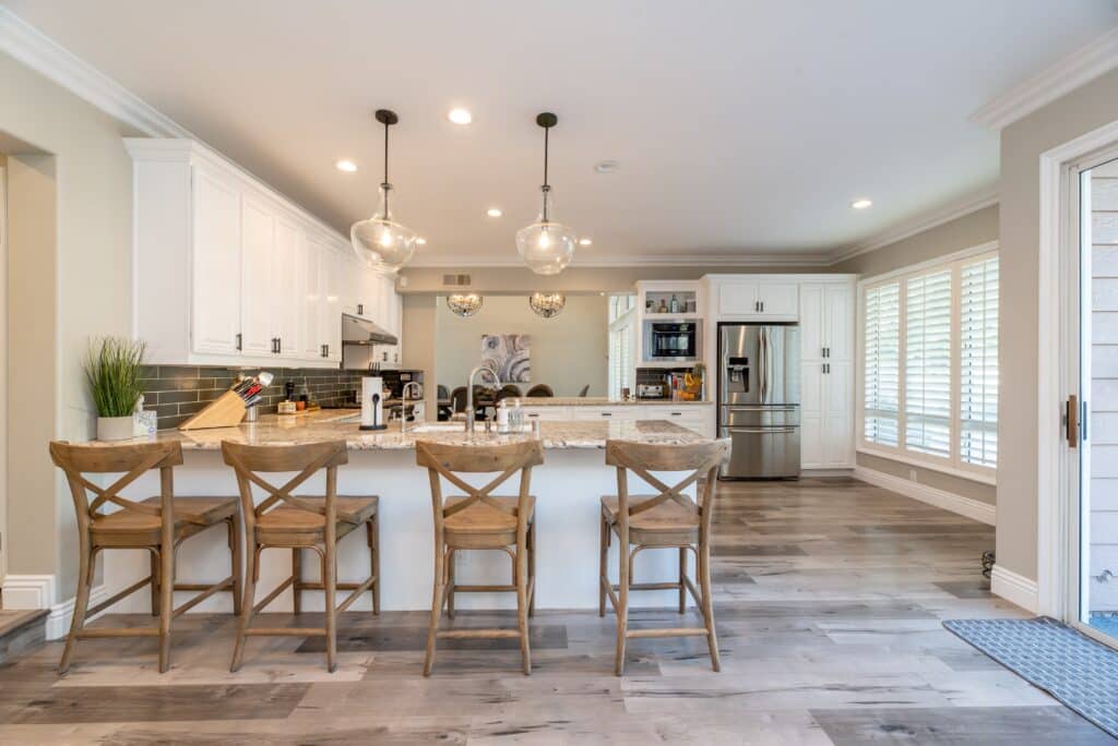 A kitchen with white cabinetry and wooden stools